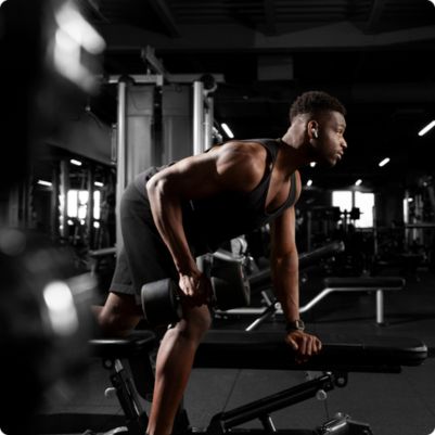 Homem treinando musculação em academia.